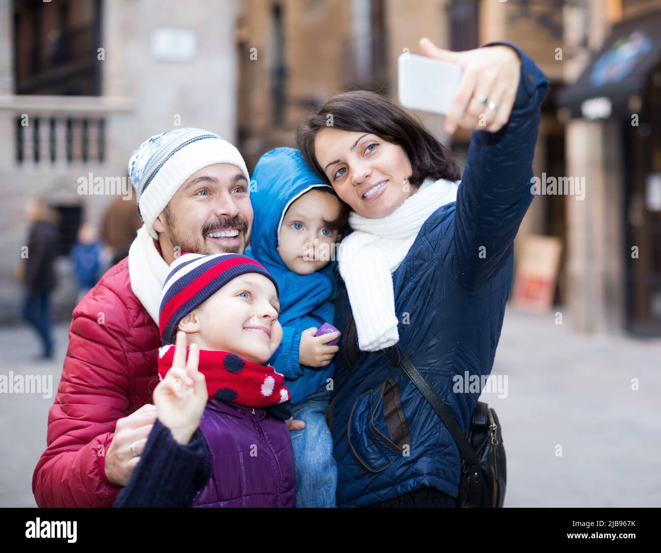 Famille souriante de quatre personnes faisant du selfie en ville Banque D'Images