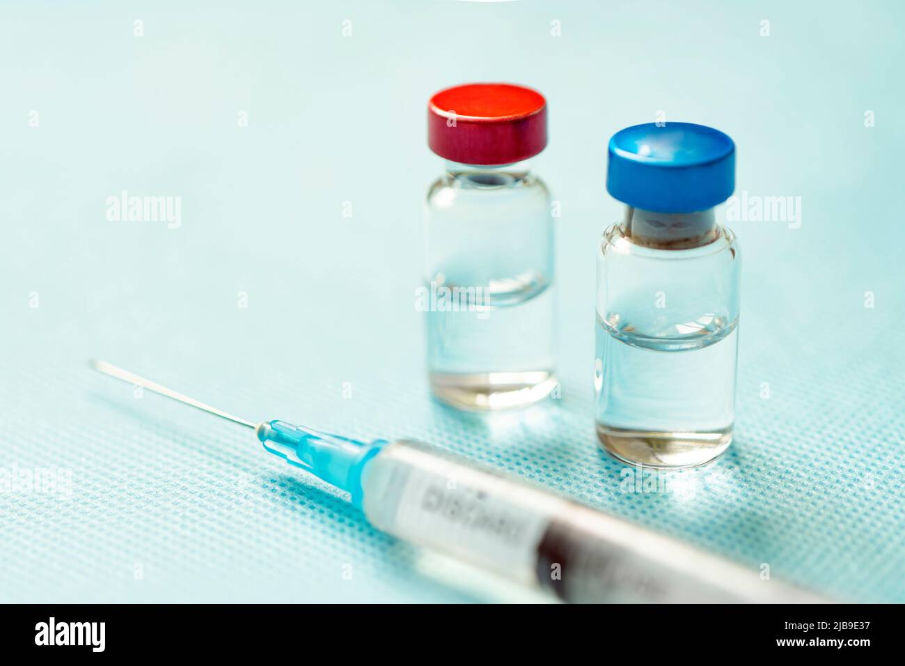 Vaccin en capsules rouges et bleues avec une seringue sur fond bleu. Le concept de médecine, de santé et de science. Vaccin contre le coronavirus. Station santé Copy Banque D'Images