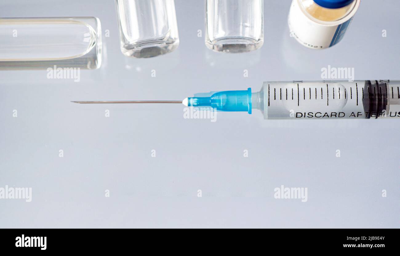 Un flacon en verre de liquide, un vaccin et une seringue médicale se rapprochent sur fond bleu. Le concept de vaccination contre le coronavirus . Bannière, cop Banque D'Images