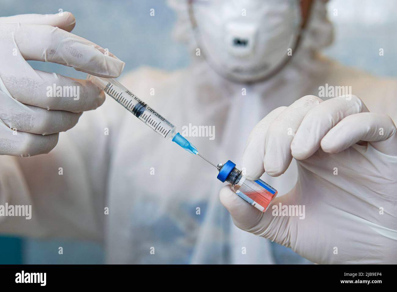 les mains du médecin injectant une aiguille de seringue dans une petite bouteille contenant un vaccin ou un médicament attribuent le virus ou la grippe Banque D'Images