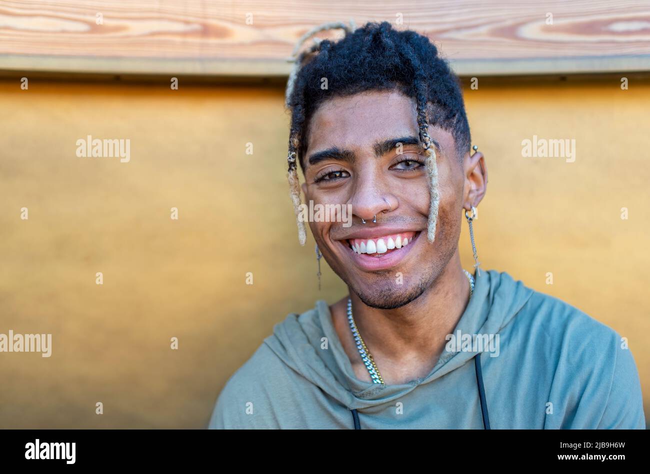 portrait en gros plan d'un homme noir alternatif qui se tient debout, froid et souriant, isolé contre un mur en bois moderne. les gens heureux sourient Banque D'Images