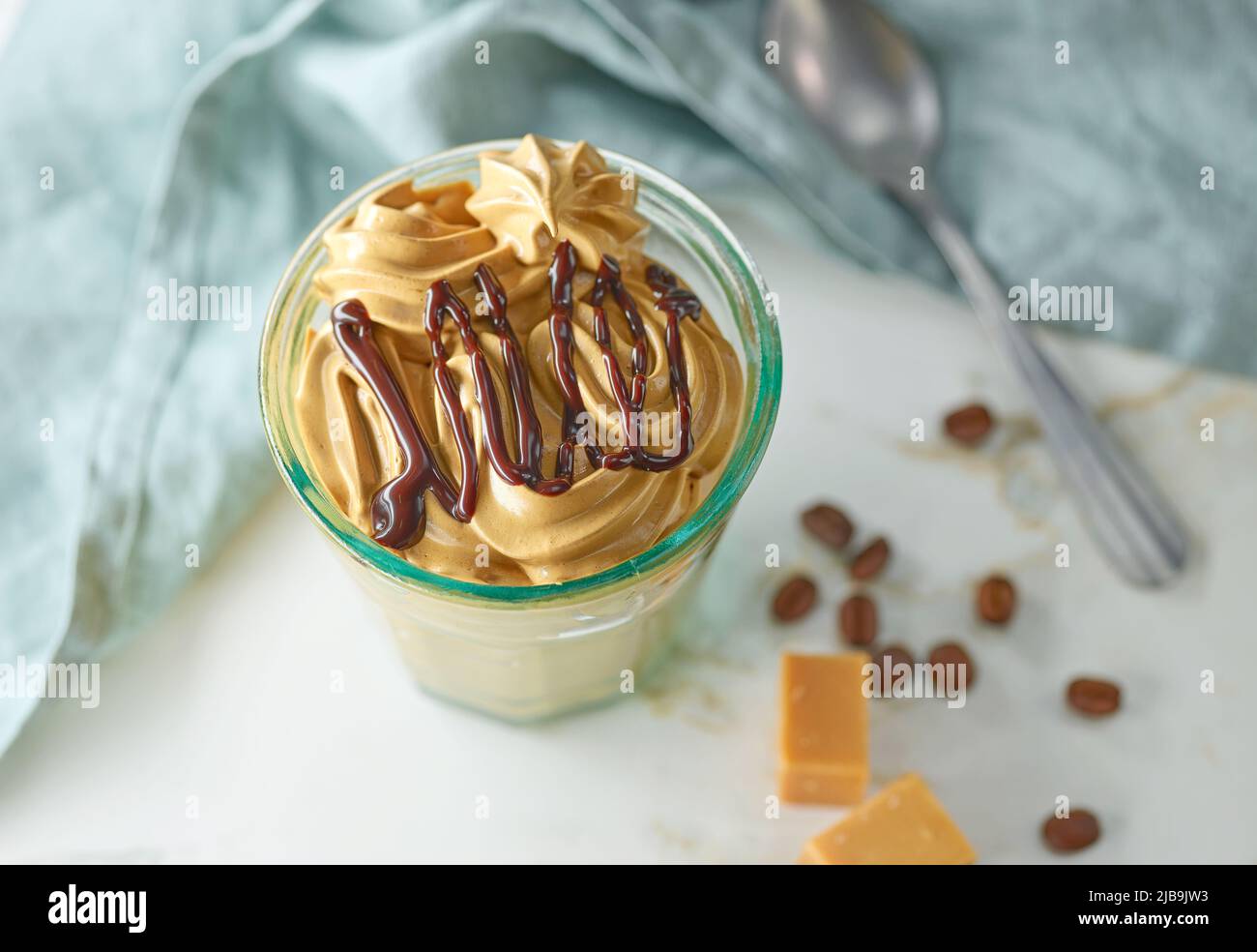 un verre de café fouetté et de mousse au caramel, décoré de chocolat fondu sur une table de cuisine Banque D'Images