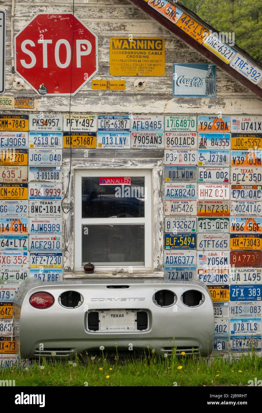 Plaques d'immatriculation de voitures de différents États et une extrémité arrière de corvette car sous une fenêtre sur le côté d'un bâtiment dans Mount Morris NY Banque D'Images