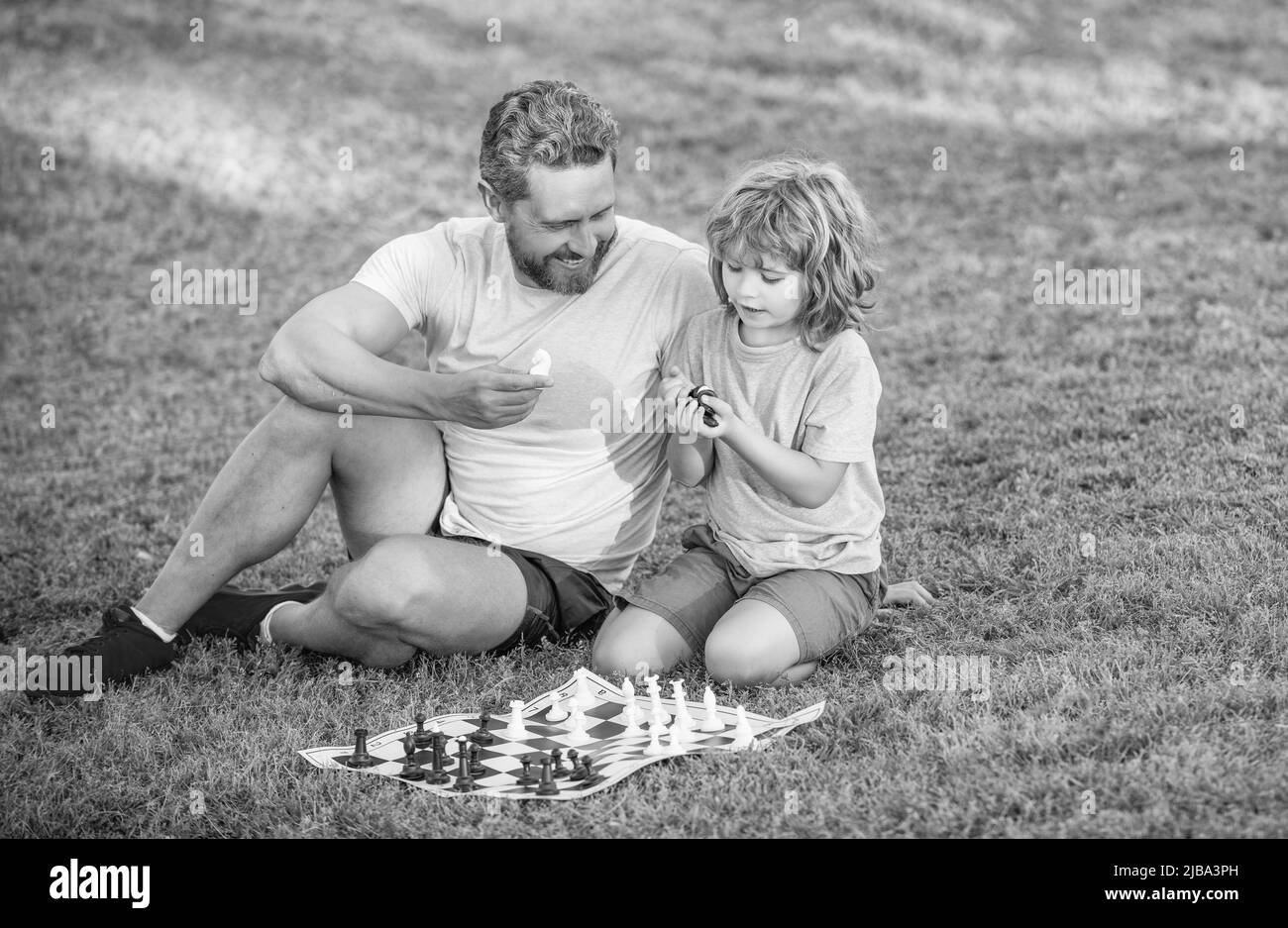 tutorat. jeu logique de daddy et d'enfant. père et fils jouant aux échecs sur l'herbe dans le parc. Banque D'Images