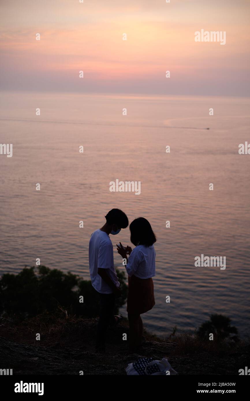 Couple profitant d'un coucher de soleil rose à Promthep Cape, Thaïlande Banque D'Images
