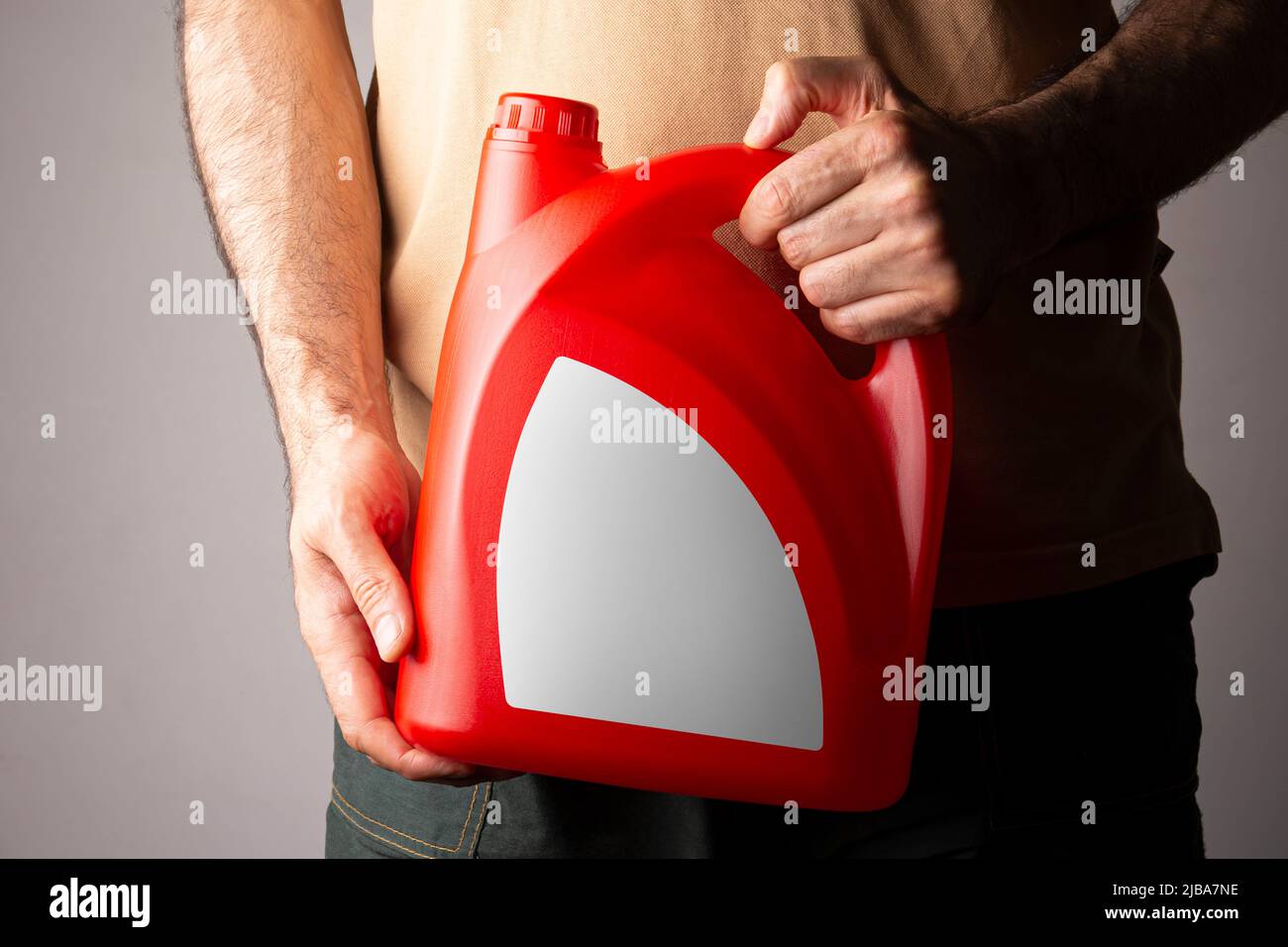 Un homme tenant une bouteille de détergent rouge de cuisine avec un capuchon fermé à sa main, modèle de série maquette modifiable prêt pour votre conception, sélecteur d'étiquette de bouteille Banque D'Images