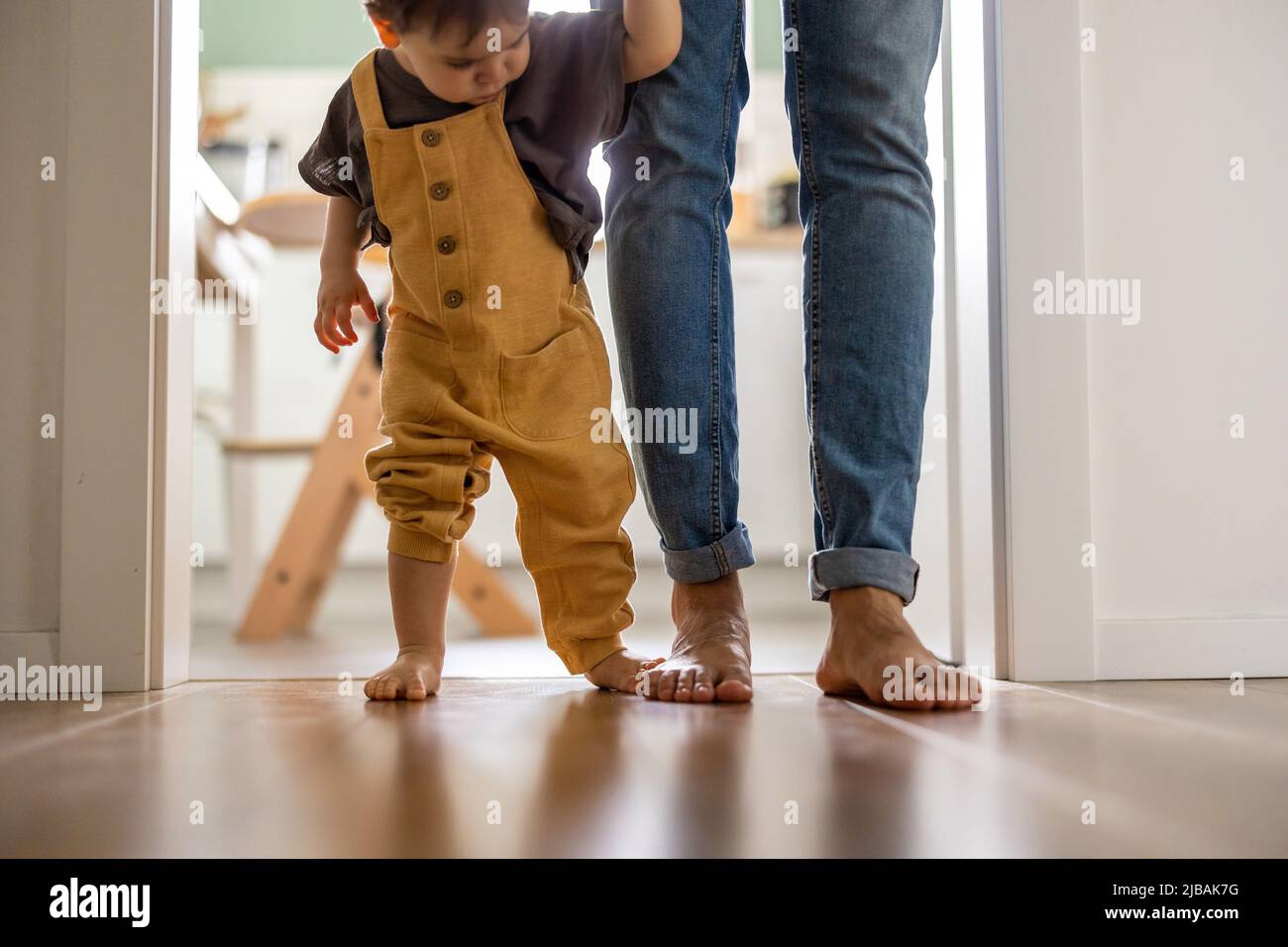 Petit garçon apprenant à marcher avec son père à côté de lui à la maison Banque D'Images