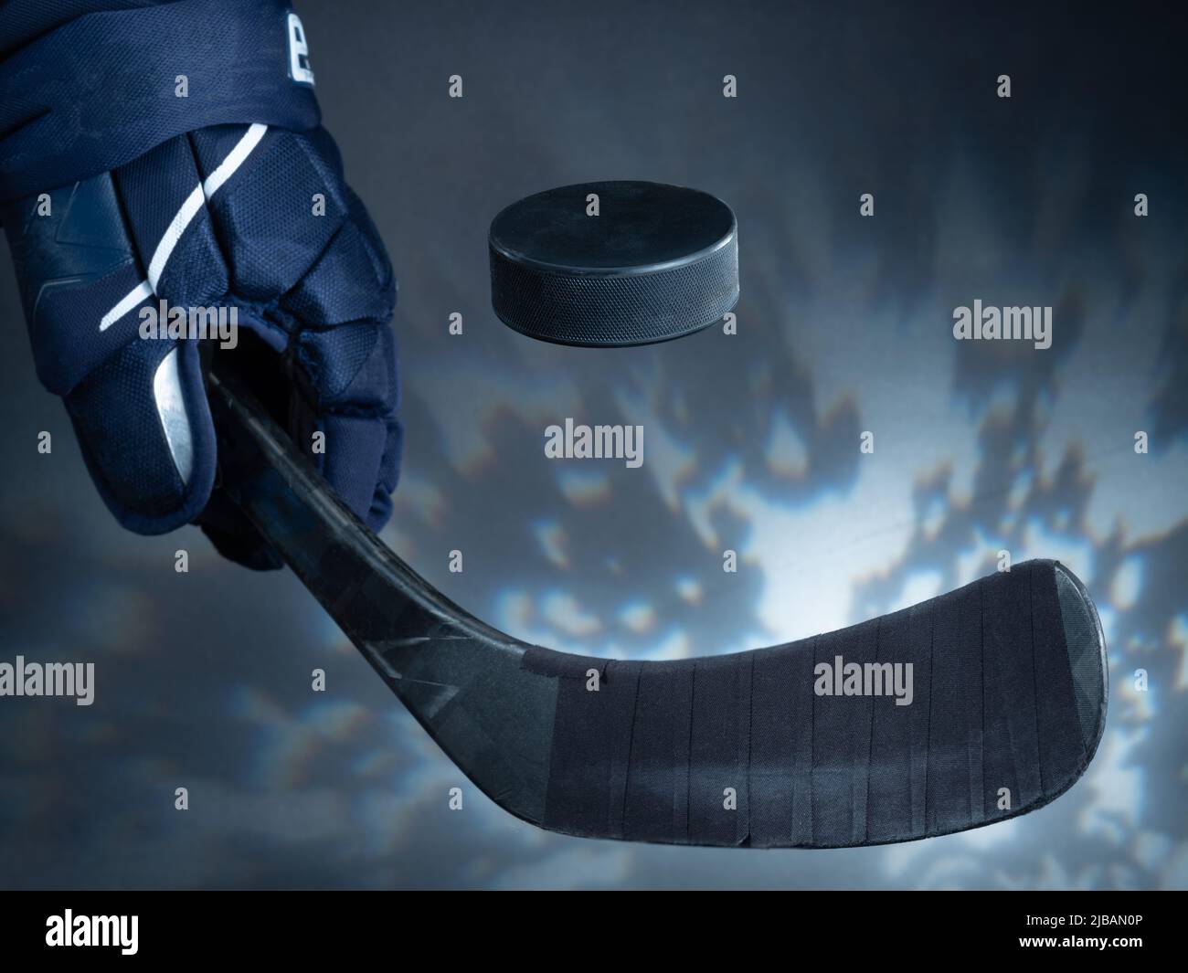 Helsinki / Finlande - 4 JUIN 2022 : gros plan d'un bâton de hockey sur glace noir qui tisse un palet sur fond de rêve. Banque D'Images
