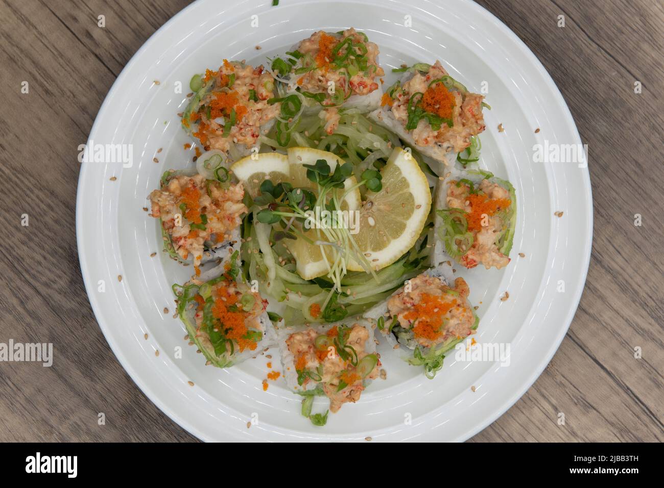 Vue sur le dessus de la cuisine asiatique, sushi roulés avec du homard et des crevettes tempura surmontée d'oignon vert et de macago pour un repas très copieux. Banque D'Images