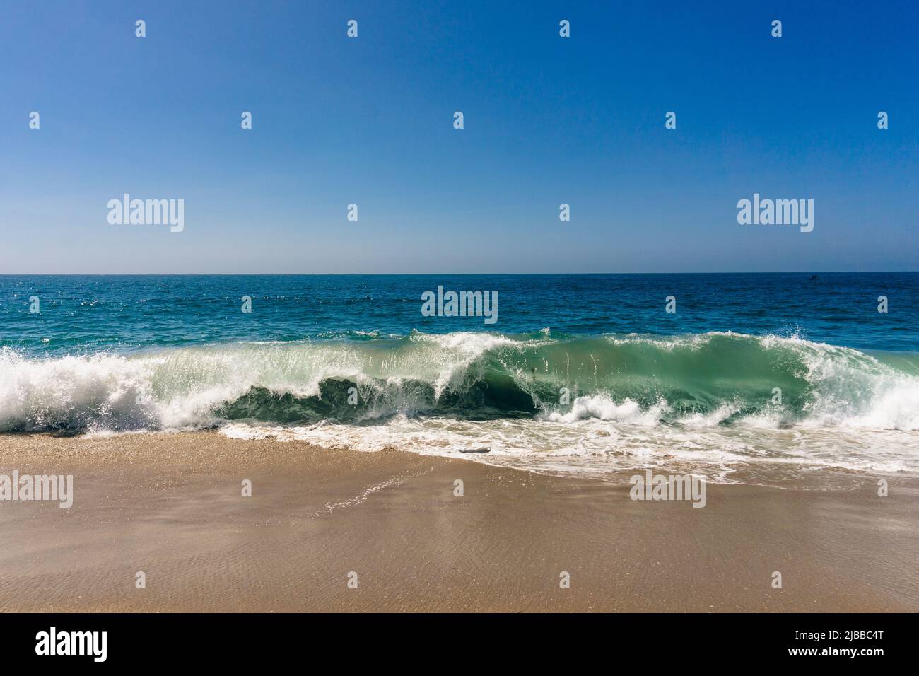 La vague de l'océan se courbe et se brise sur la plage de sable de Californie lors d'une journée ensoleillée Banque D'Images
