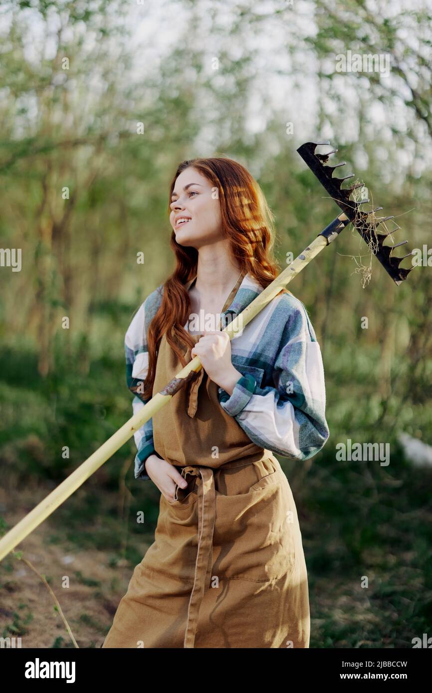 Une femme paysanne en vêtements de travail et un tablier travaille à l' extérieur dans la nature et tient un râteau pour rassembler l'herbe Photo  Stock - Alamy
