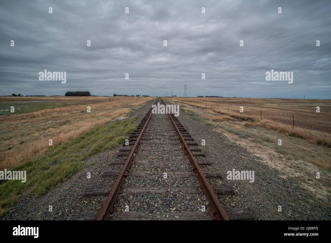 Un chemin de fer menant à la distance et s'évanouissant à l'horizon dans des prairies plates dans la vallée centrale de la Californie, États-Unis. Banque D'Images