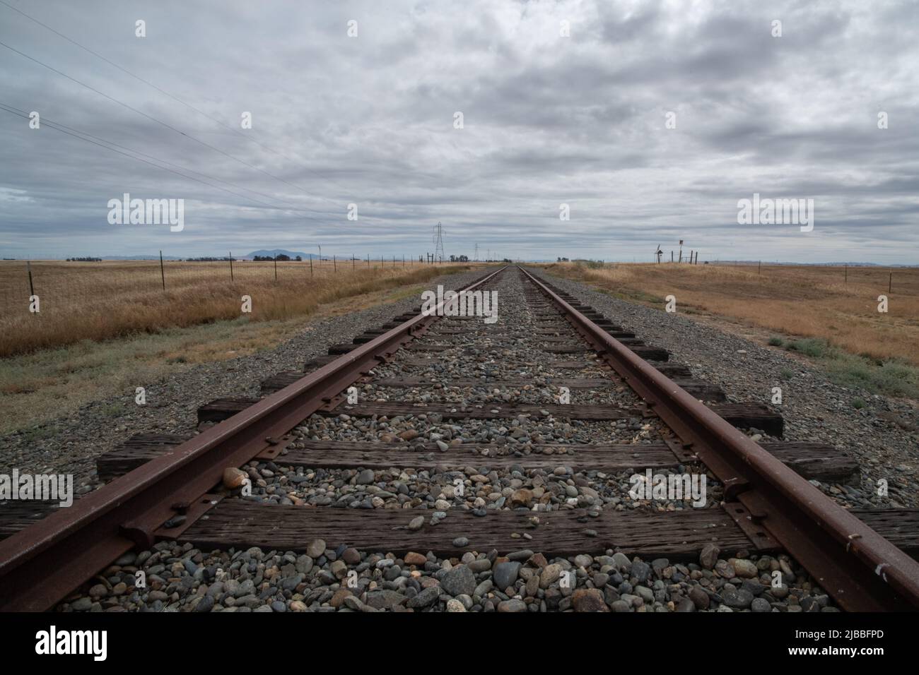 Un chemin de fer menant à la distance et s'évanouissant à l'horizon dans des prairies plates dans la vallée centrale de la Californie, États-Unis. Banque D'Images