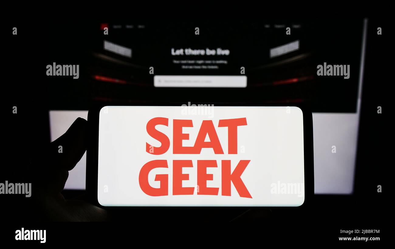 Personne tenant un smartphone avec le logo de la société américaine de plateforme de billets SeatGeek Inc. À l'écran devant le site Web. Mise au point sur l'affichage du téléphone. Banque D'Images