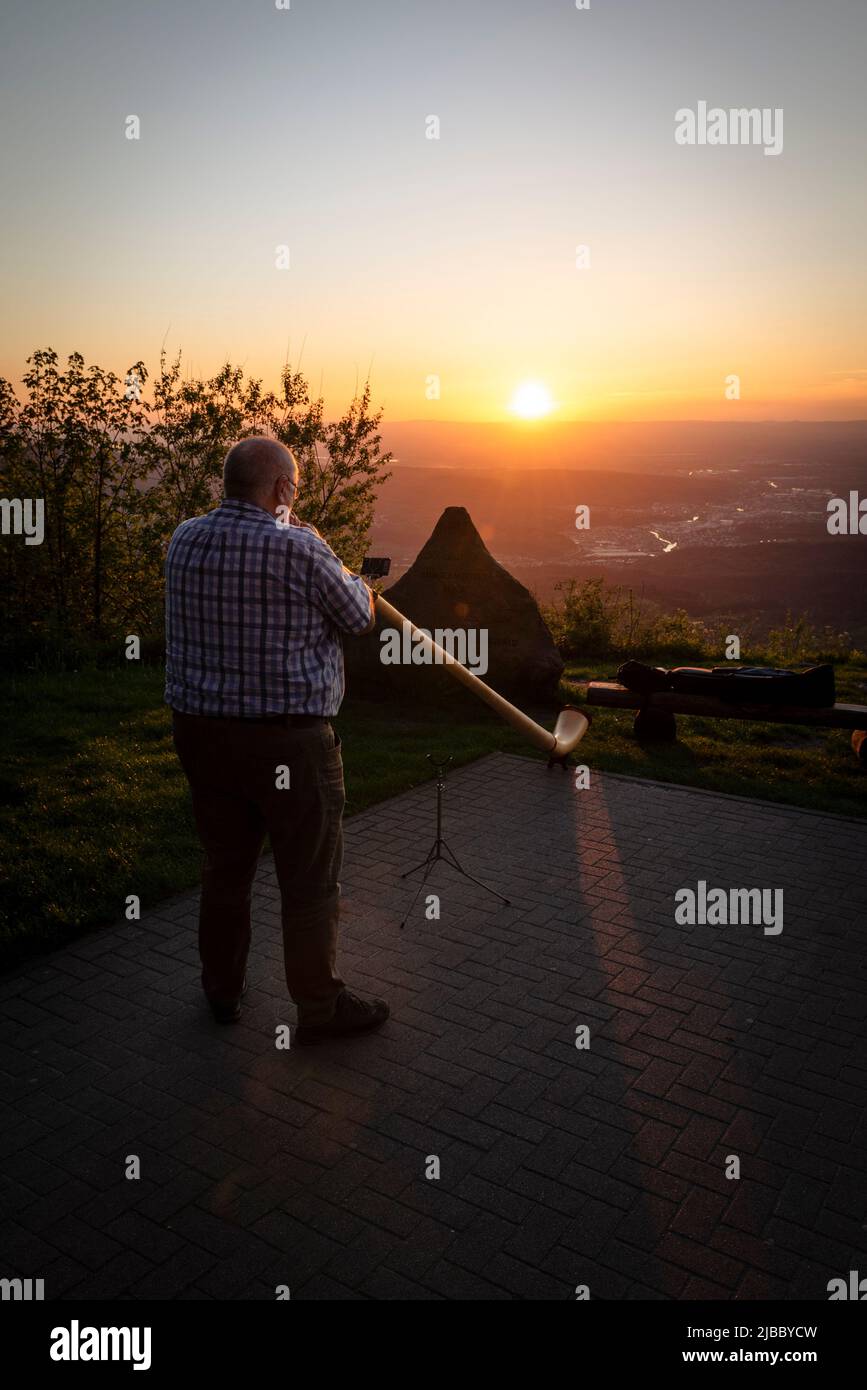 Un homme joue un Alphorn au point de vue de Devil's Mill au coucher du soleil sur la vallée de Murgtal dans la Forêt Noire, Bade-Wurtemberg, Allemagne. Banque D'Images