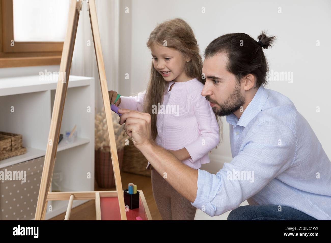 Papa aimant et fille en dessinant ensemble à bord avec des craies Banque D'Images