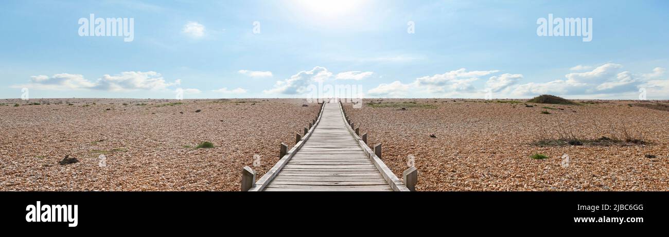 Dungeness Headland est une plage de galets balayée par le vent, semblable à un désert et forlorn. Ce chemin de planche en bois mène à travers les pierres jusqu'à la Manche. Banque D'Images
