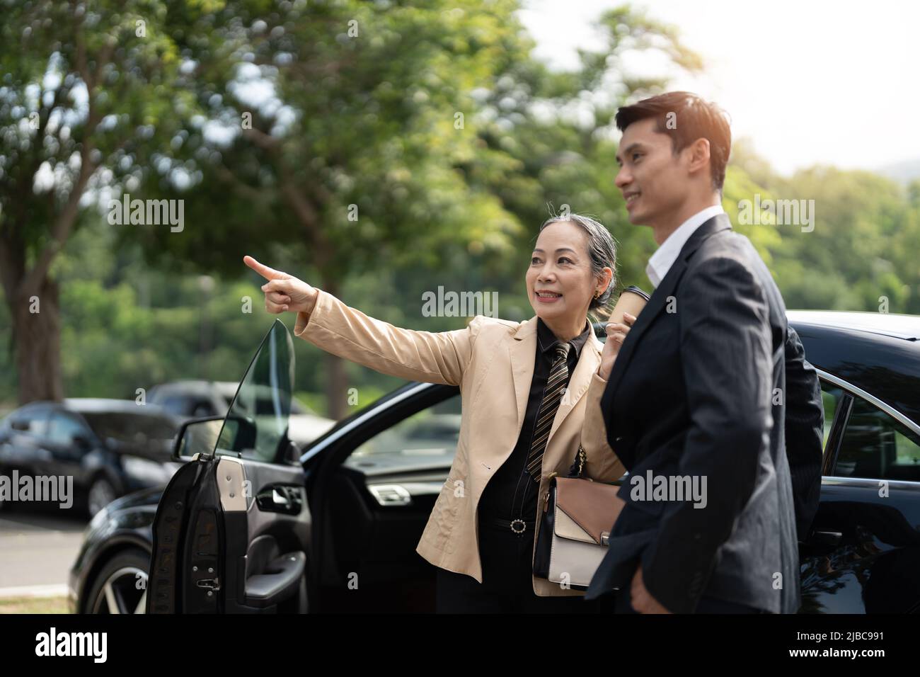 Bonne vieille femme d'affaires asiatique discussion sur le nouveau projet avec un jeune collègue asiatique au parking. Banque D'Images