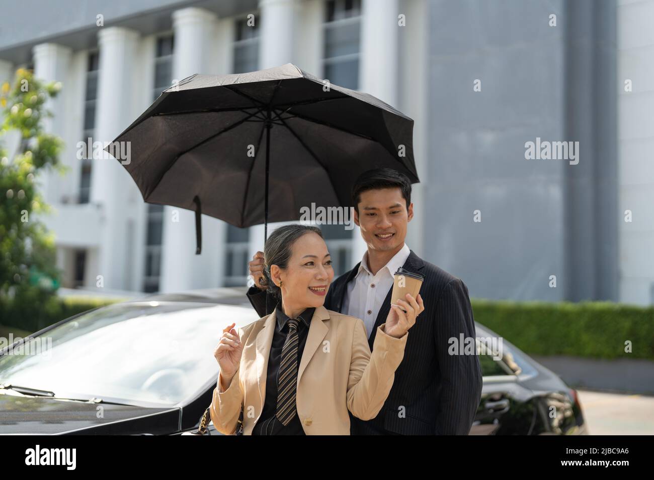 Bonne vieille femme d'affaires asiatique discussion sur le nouveau projet avec un jeune collègue asiatique au parking. Banque D'Images