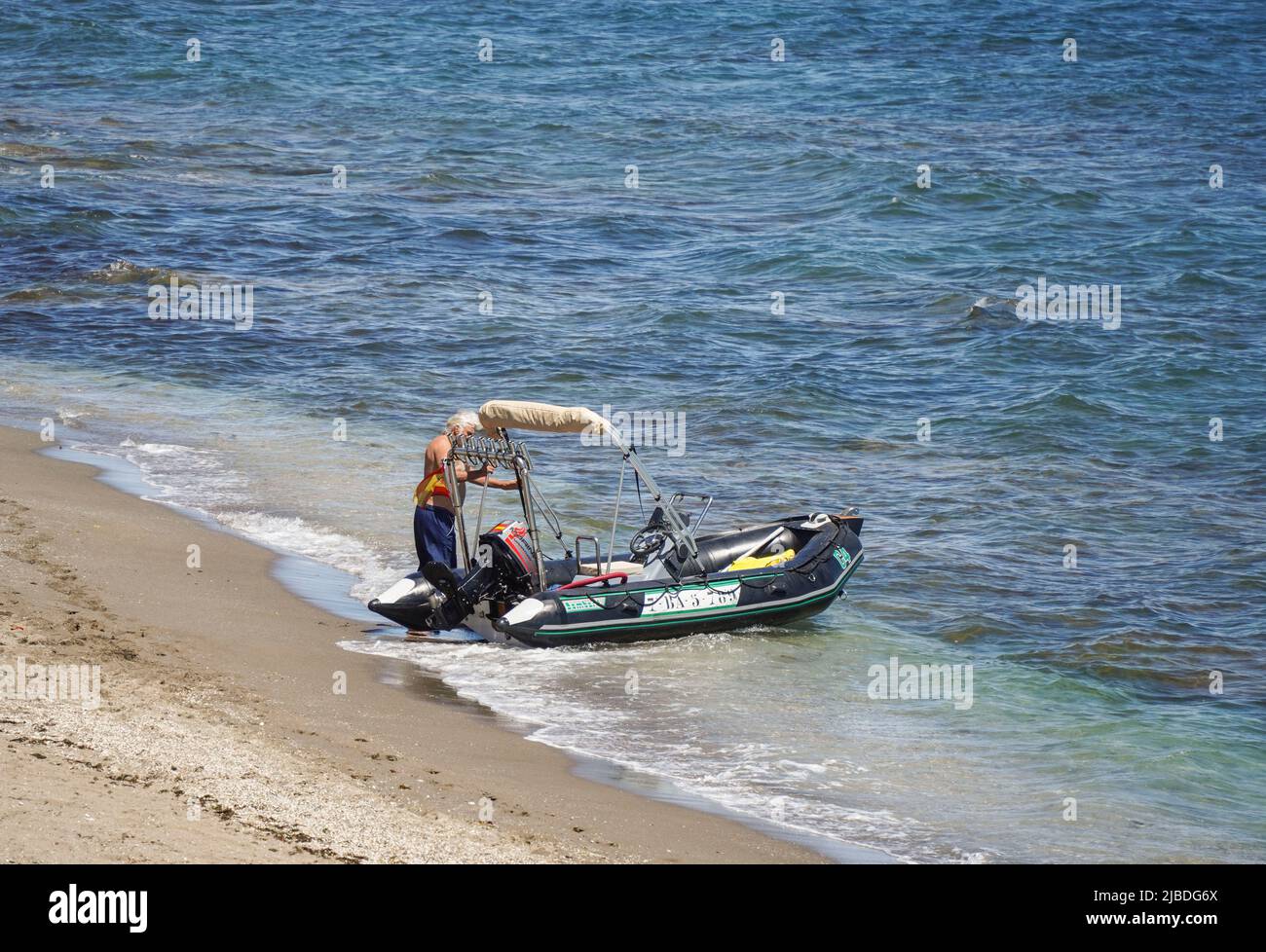 Homme avec Zodiac sur la plage, Costa del sol, la Cala, Andalousie, Espagne. Banque D'Images
