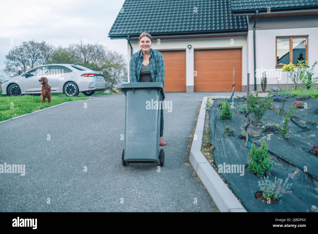 Une fille européenne de 20s a sorti la poubelle pour trier les ordures près d'une maison Banque D'Images