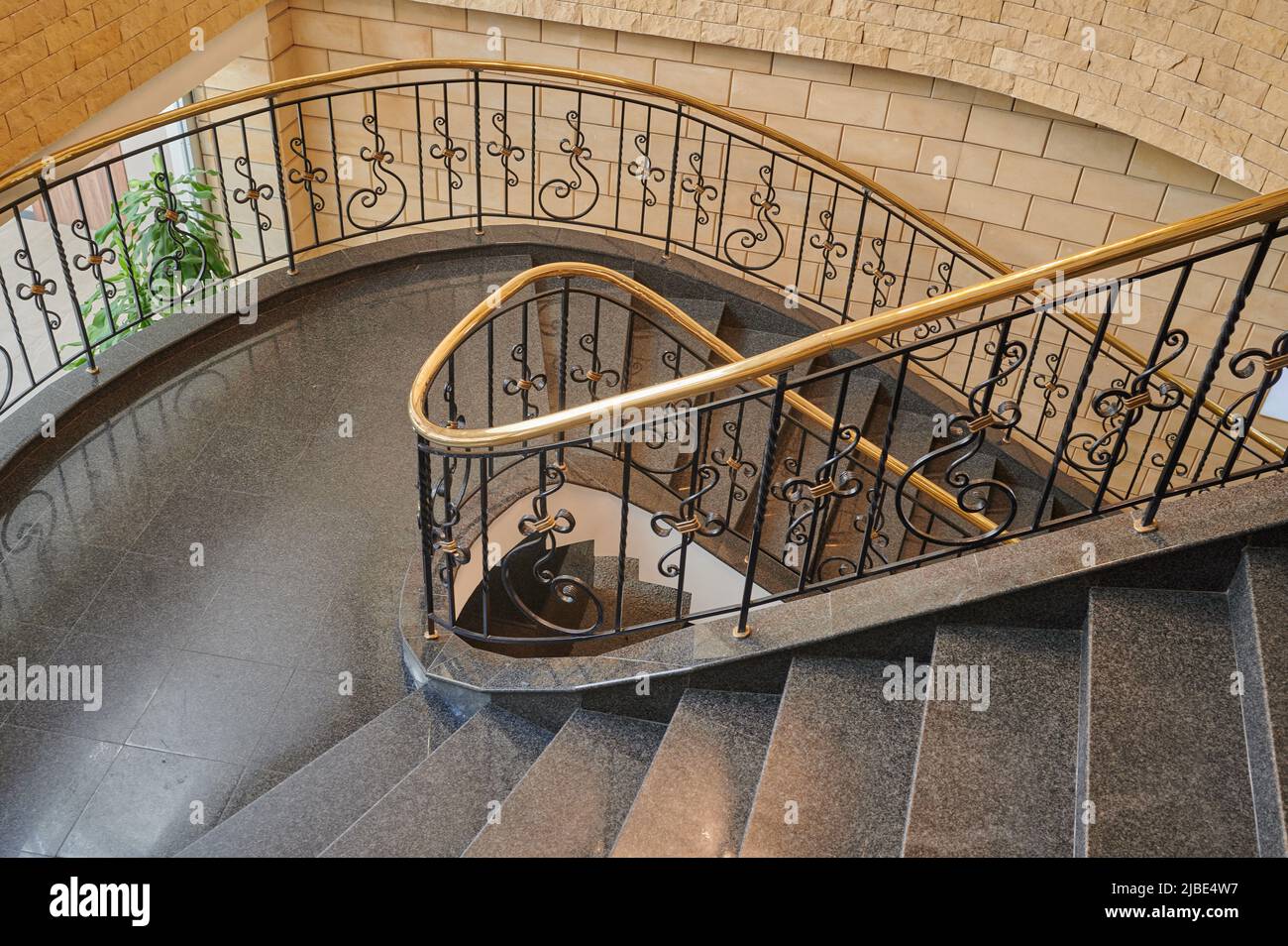 escalier en colimaçon à l'intérieur avec sol en marbre et élégants balusters en fer forgé avec rampes en bois Banque D'Images