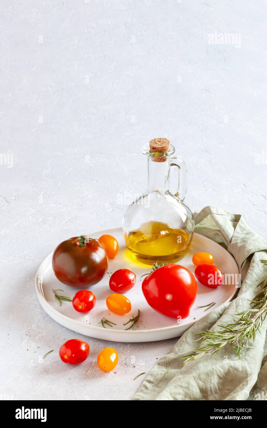 Plateau rond avec différentes variétés de tomates, sel et huile d'olive Banque D'Images