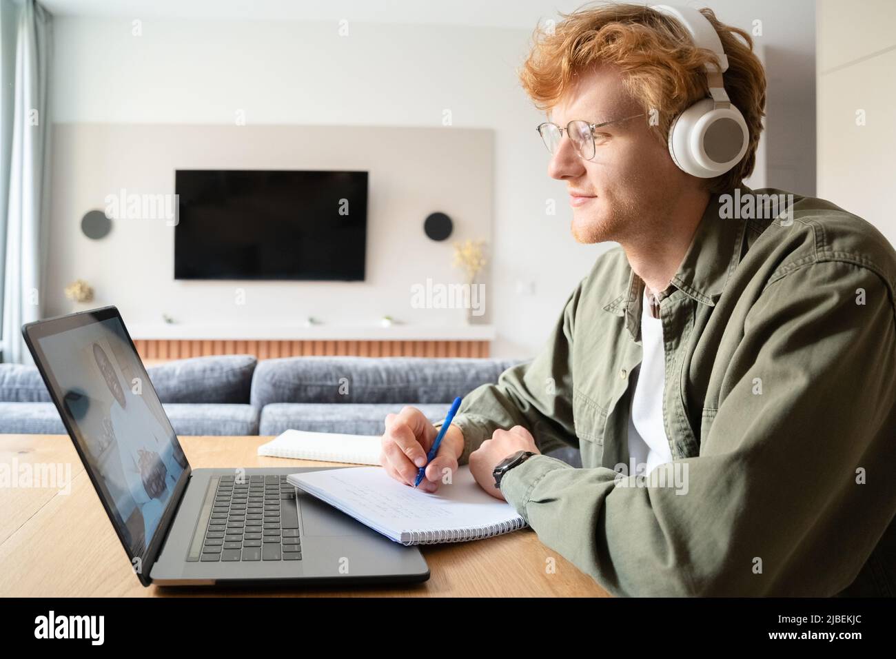 Un jeune homme irlandais au gingembre dans un casque d'écoute d'un coach professionnel lors d'un séminaire en ligne Banque D'Images