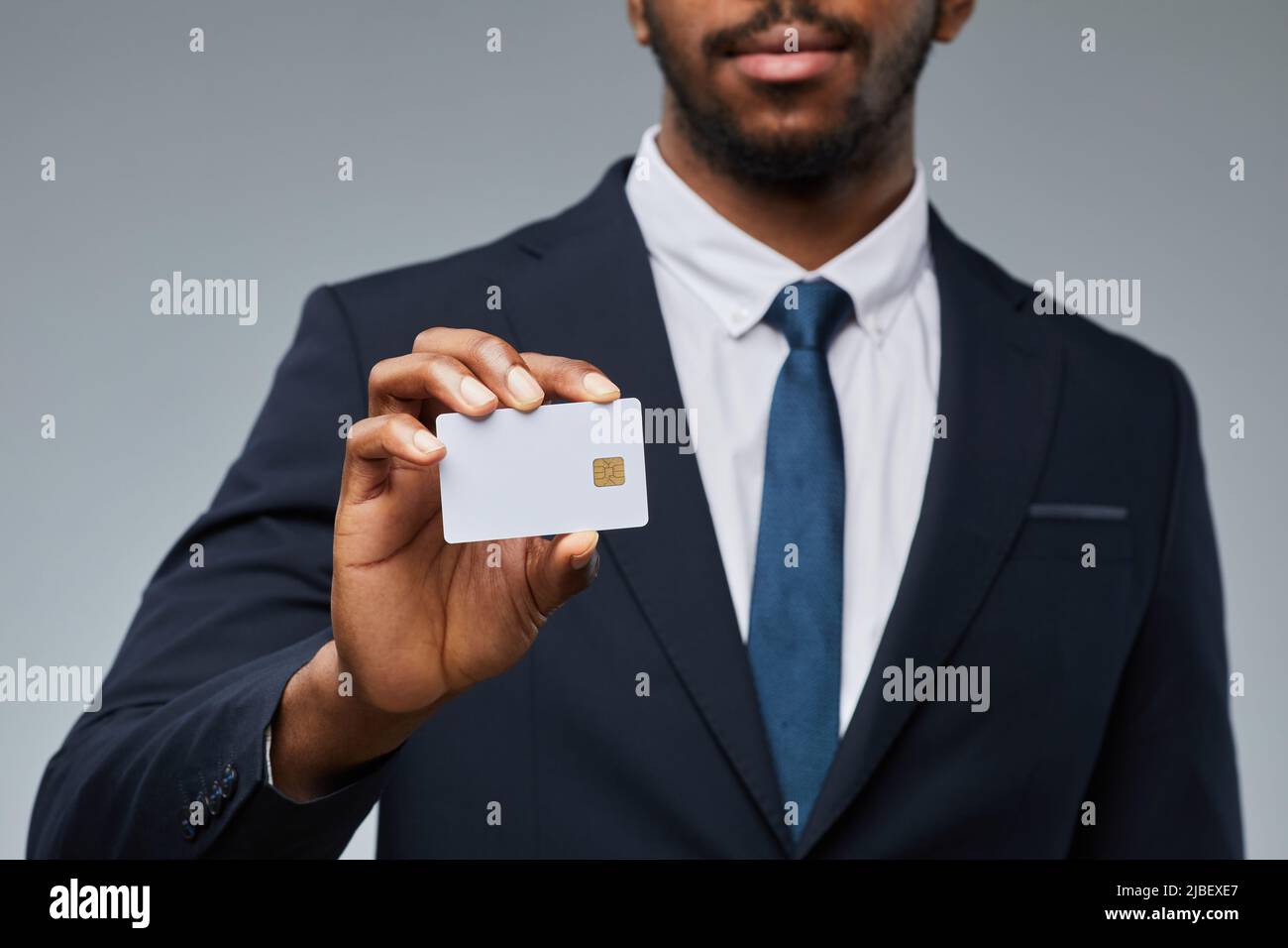 Gros plan d'un homme d'affaires noir tenant une maquette de carte de crédit vierge et montrant à l'appareil photo, espace de copie Banque D'Images