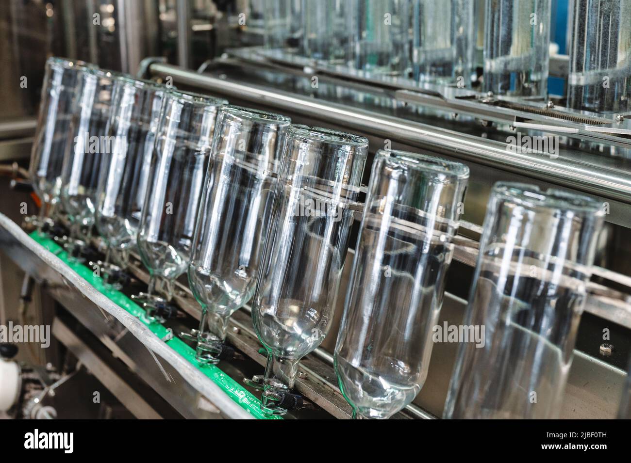 Rangée de bouteilles en verre vides sur convoyeur automatique à l'usine Banque D'Images