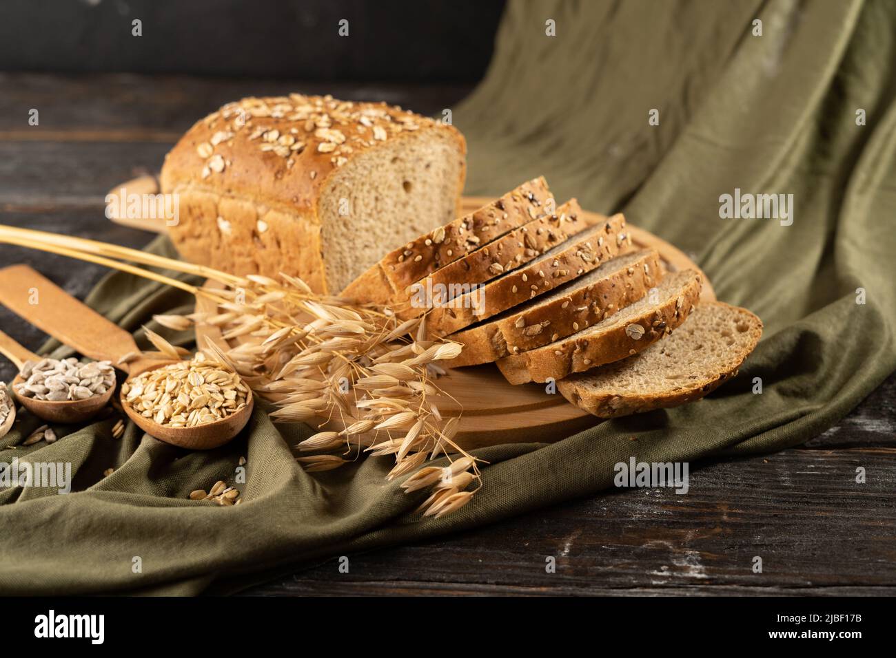 Pain de blé entier biologique prêt à manger. Pain multi-grains sur une planche de bois avec un panier de paille et un tissu rustique à l'arrière-plan Banque D'Images