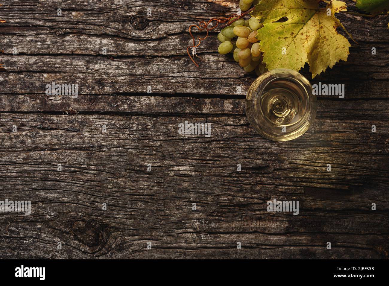 Vin blanc dans un verre, raisins et branches de raisin sur la table. Vue de dessus. Copiez de l'espace pour votre texte. Banque D'Images