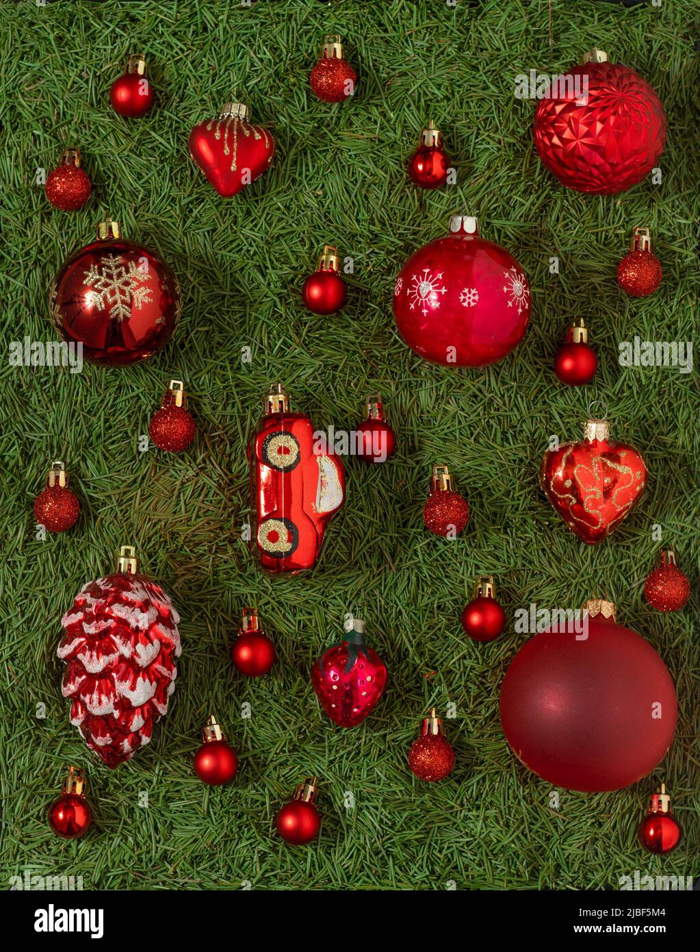 Un ensemble de différents jouets rouges de Noël sur un fond vert d'aiguilles d'arbre de Noël. Boule rouge. Décor et décorations. Concept de la nouvelle année. Banque D'Images