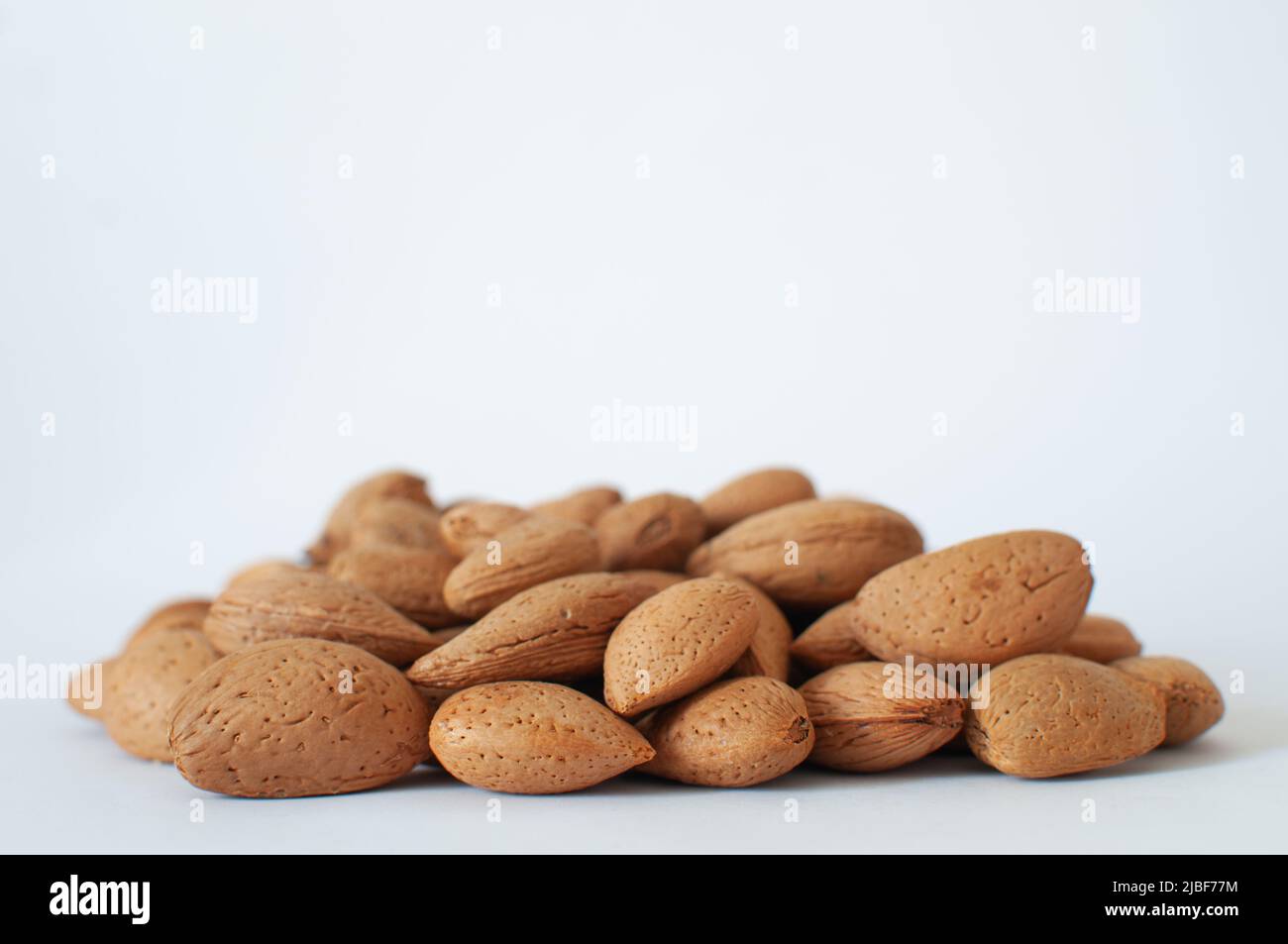 Amandes organiques, concentration sélective sur tas d'amandes turques naturelles à coque dure, isolées sur fond blanc. Banque D'Images