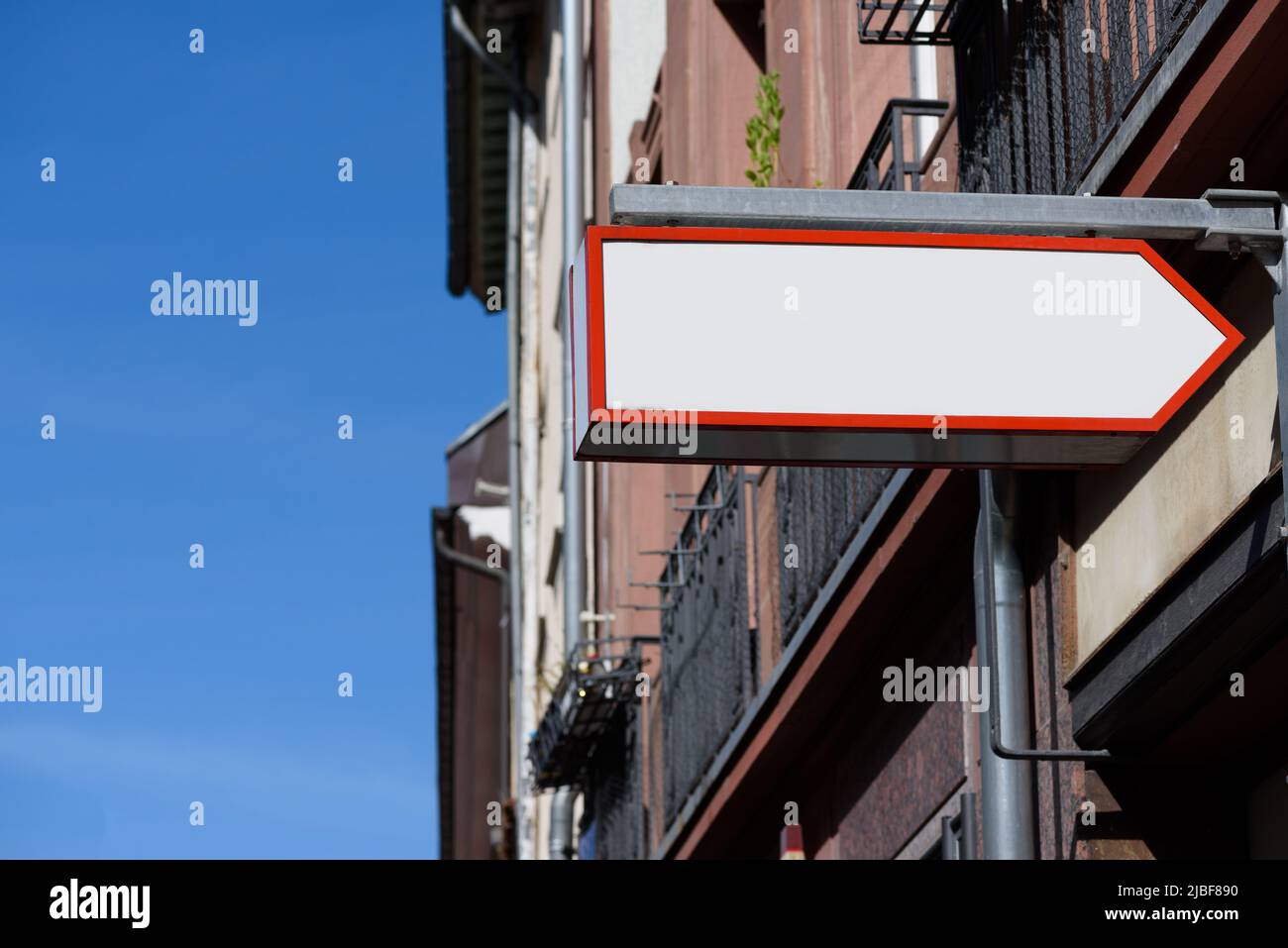 Le pointeur de flèche vierge stocke le panneau sur la rue suspendu sur le mur. Vider la maquette du panneau d'affichage en plastique. Banque D'Images