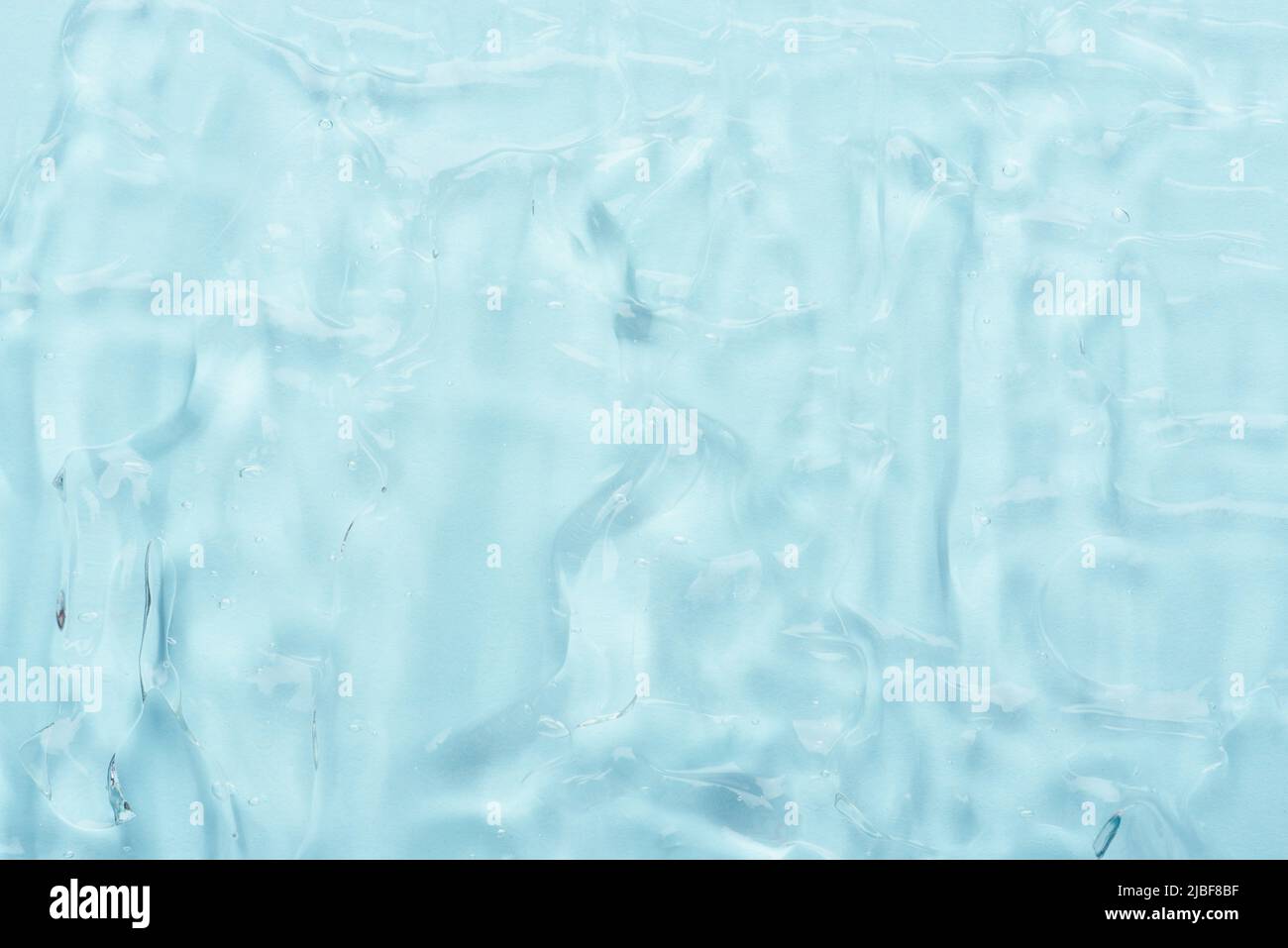 Gel d'aloès cosmétique transparent avec bulles sur fond bleu texture vue de dessus Banque D'Images