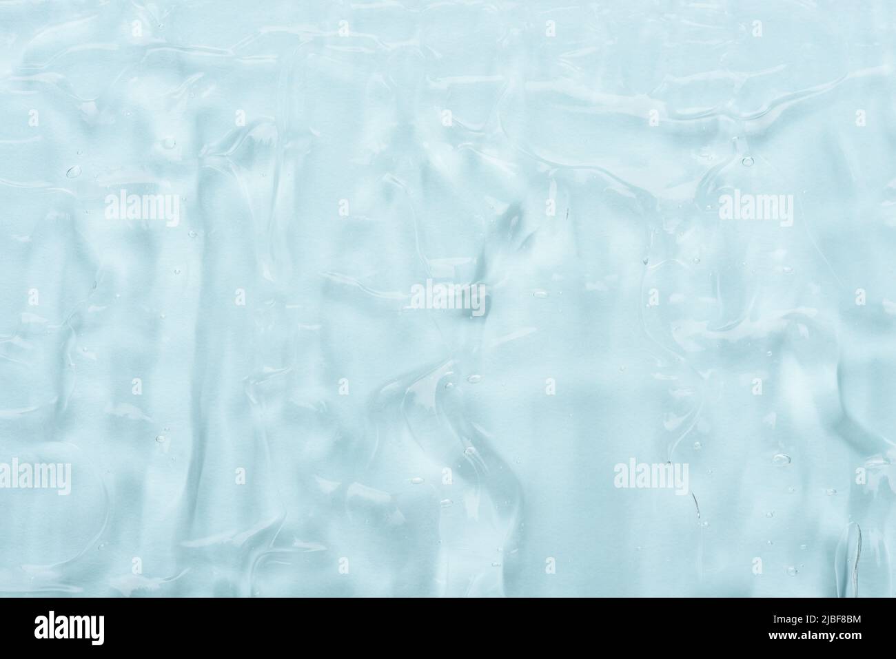 Gel cosmétique transparent pour la peau avec bulles sur fond bleu texture vue de dessus Banque D'Images