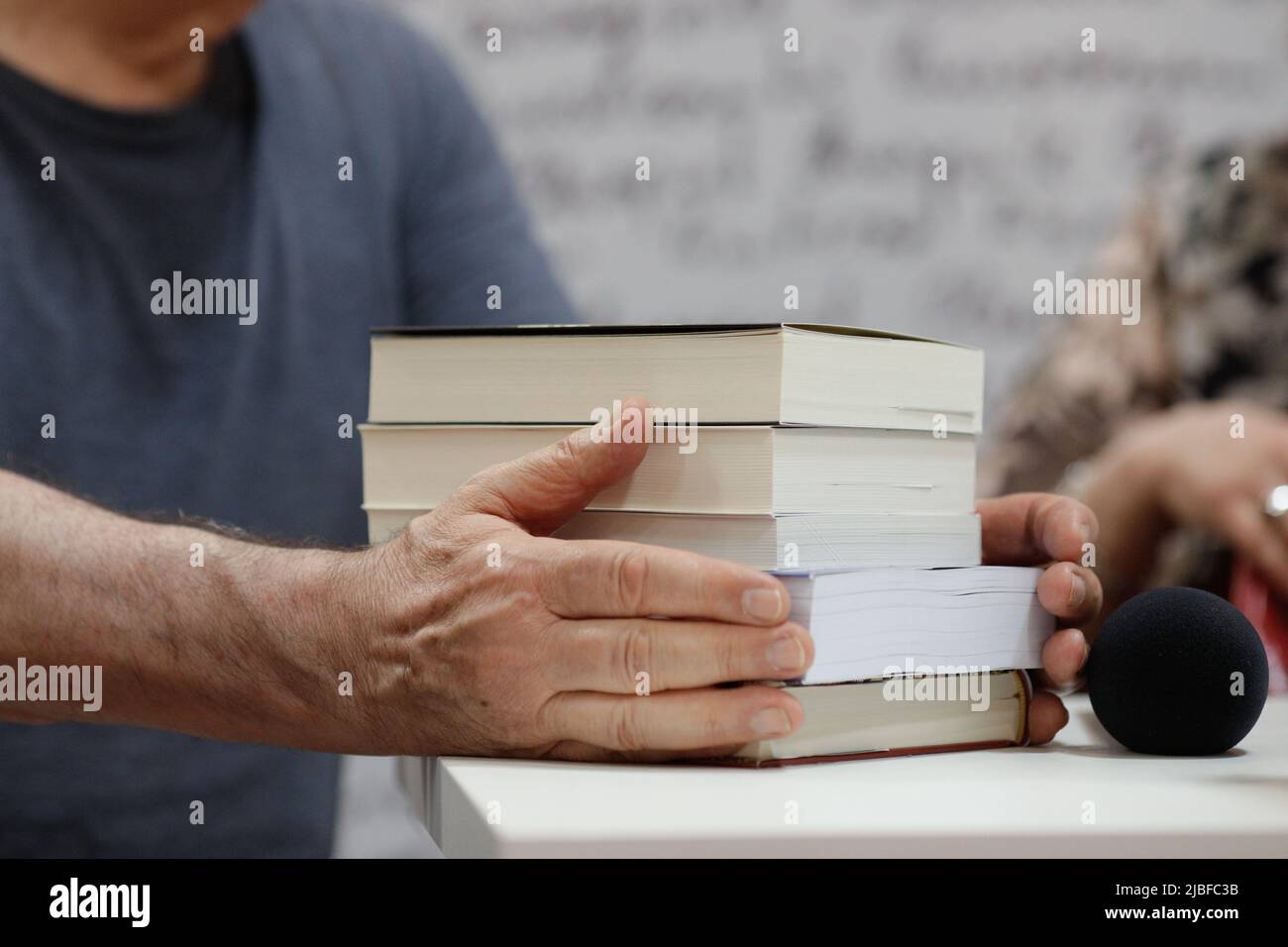 Profondeur de champ peu profonde (mise au point sélective) détails avec les mains d'un homme sur une pile de livres pendant un événement de libération de livre. Banque D'Images