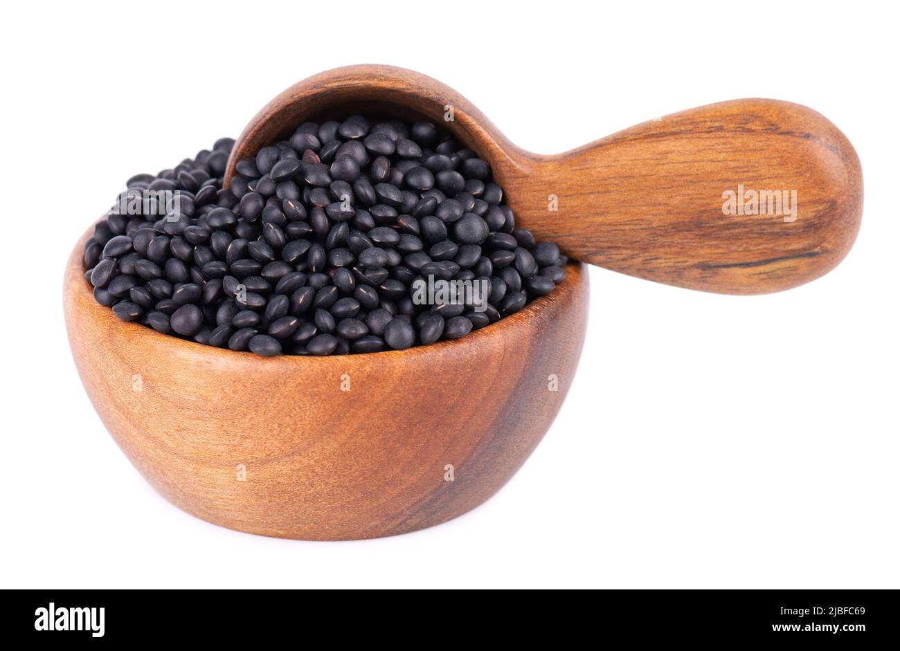 Lentilles noires dans un bol et une cuillère en bois, isolées sur fond blanc. Pile de grains de lentilles de béluga secs Banque D'Images