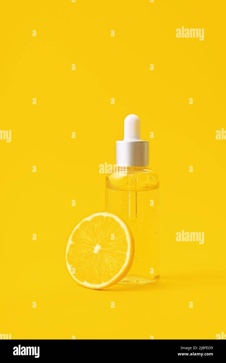 Ampoule de formule de vitamine C. Sérum en flacon transparent avec citron sur fond jaune vif. Concept de beauté et de santé. Maquette pour votre conception avec espace de copie. Banque D'Images