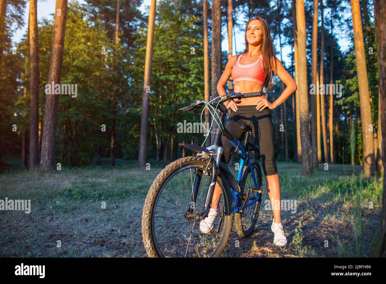 Posez la femme avec un vélo dans la forêt Banque D'Images