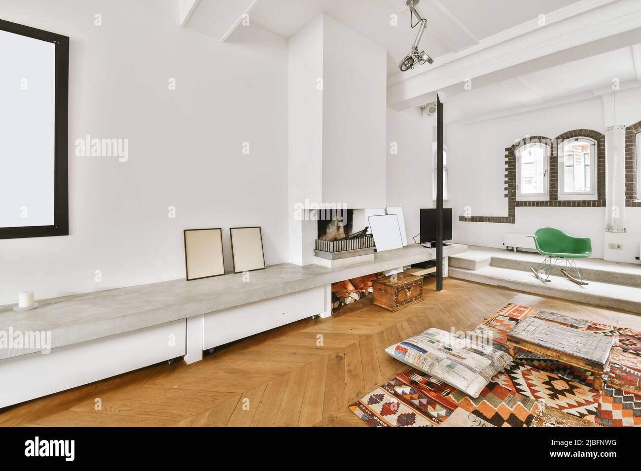 Confortables coussins moelleux et tapis ornemental de style oriental dans le salon spacieux avec parquet et cheminée dans villa lumineuse à la lumière du jour Banque D'Images