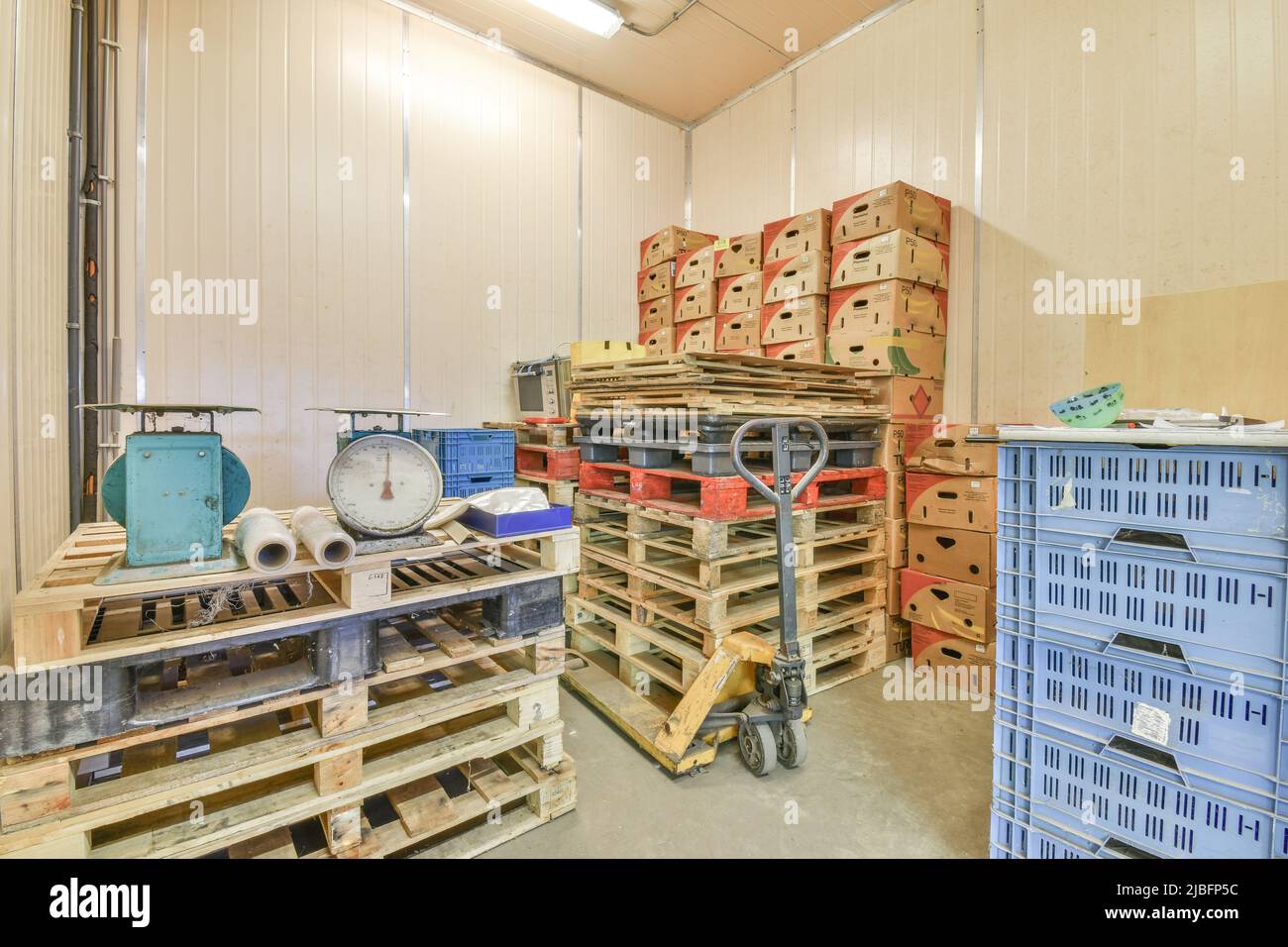 Anciennes balances en métal et emballage en plastique laminé placés sur une pile de palettes en bois dans un entrepôt moderne avec boîtes en carton et conteneurs en plastique Banque D'Images