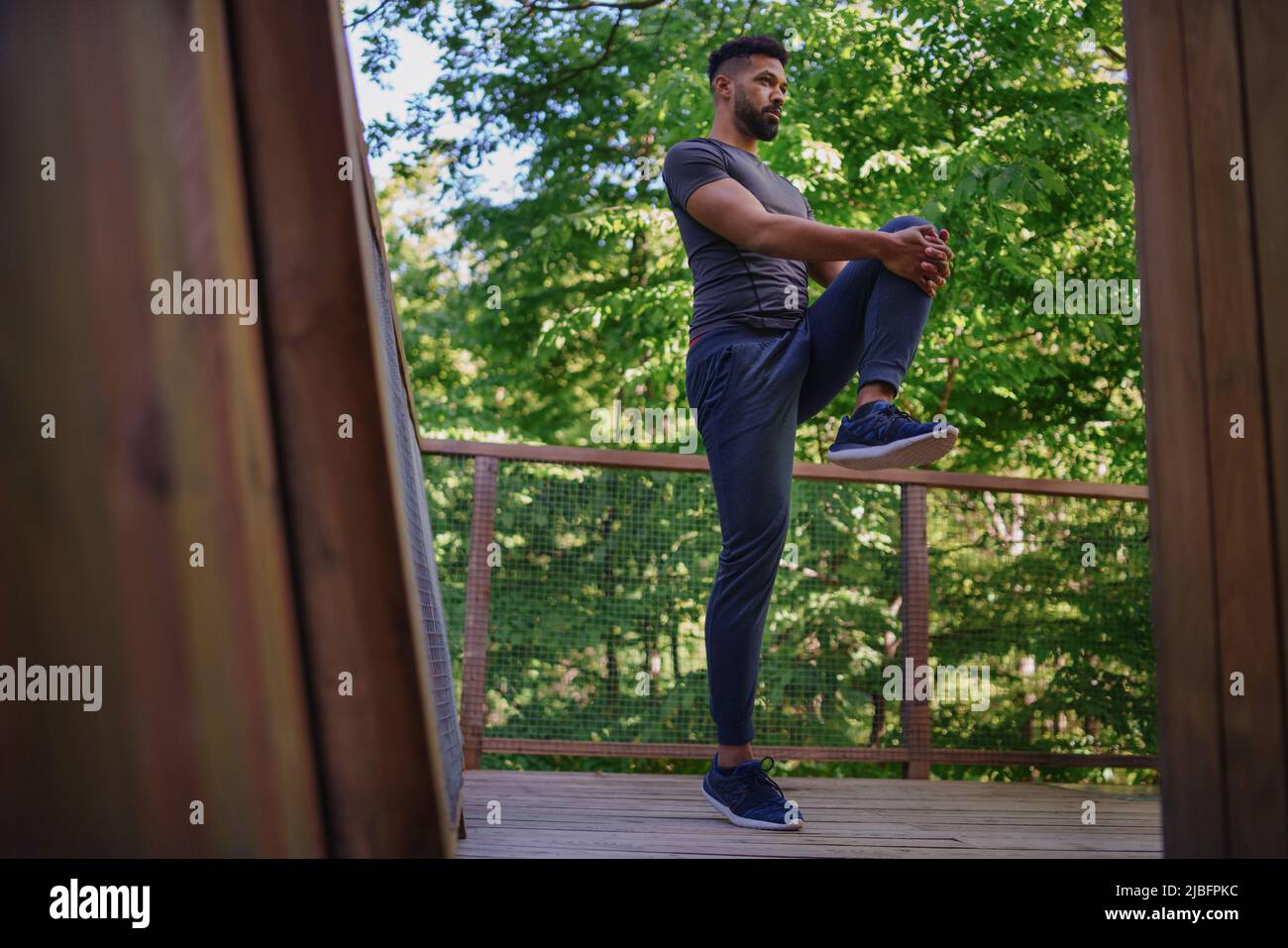 Jeune homme faisant de l'exercice à l'extérieur sur la terrasse de la maison d'arbre, week-end loin et concept numérique de détox. Banque D'Images