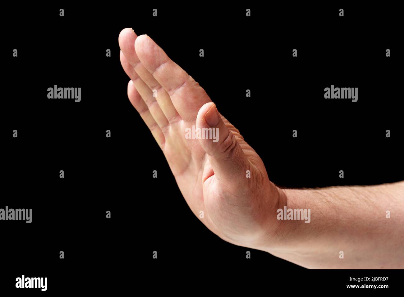Un homme montre un geste d'arrêt. Gros plan d'une main mâle sur fond noir Banque D'Images