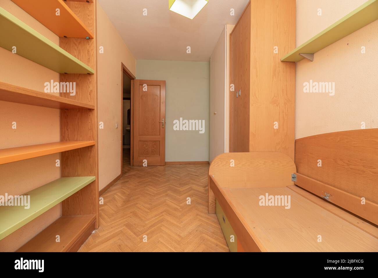 Chambre jeune avec meubles en pin avec étagères, bureau et armoires assorties et lit sans matelas Banque D'Images
