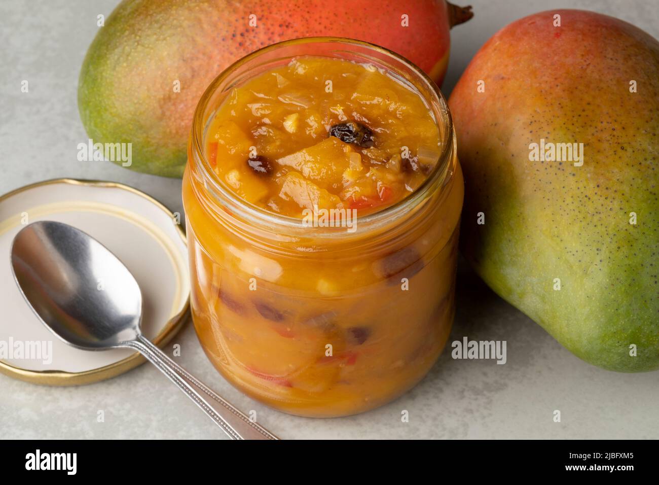 Pot en verre avec chutney de mangue maison et gros plan de mangue fraîche Banque D'Images