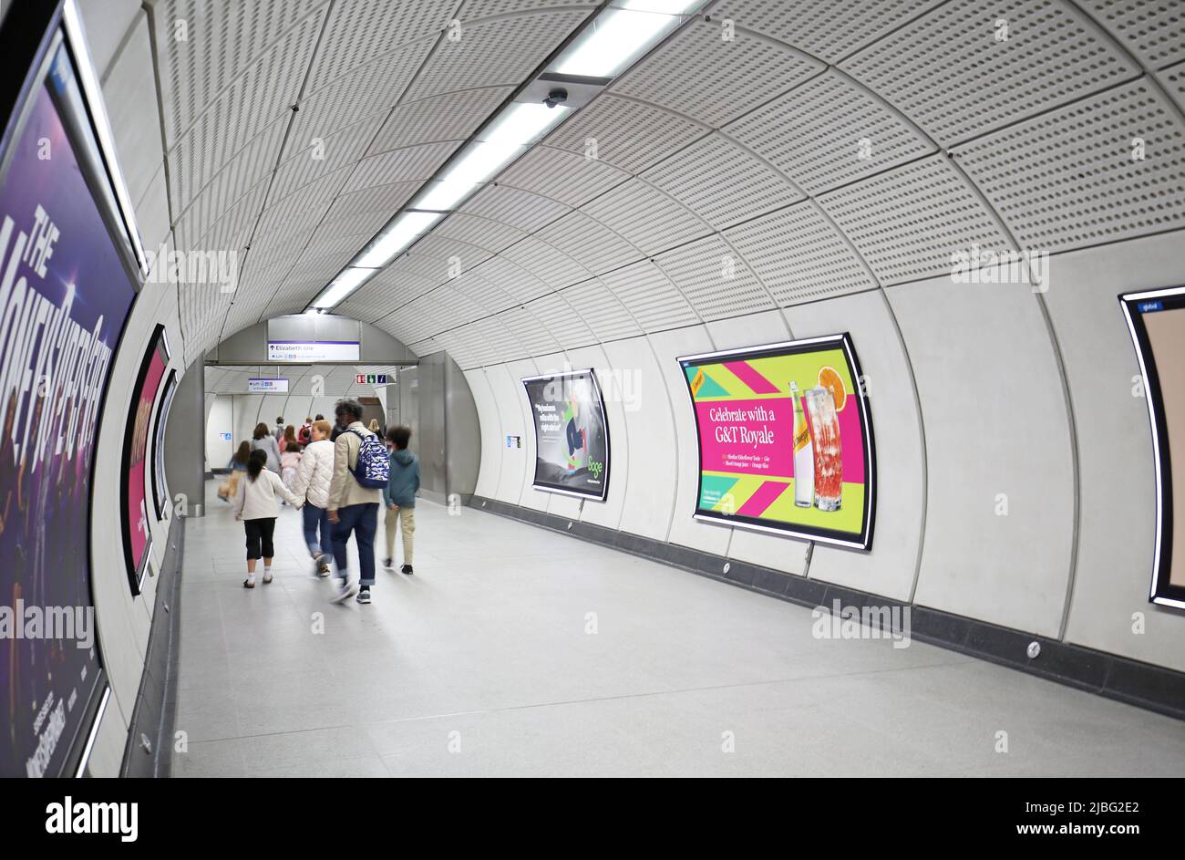 Londres, Royaume-Uni. Tunnels d'accès souterrains à la gare de Liverpool Street sur le nouveau réseau Elizabeth Line (Crossrail). Affiche le groupe de famille passant par. Banque D'Images