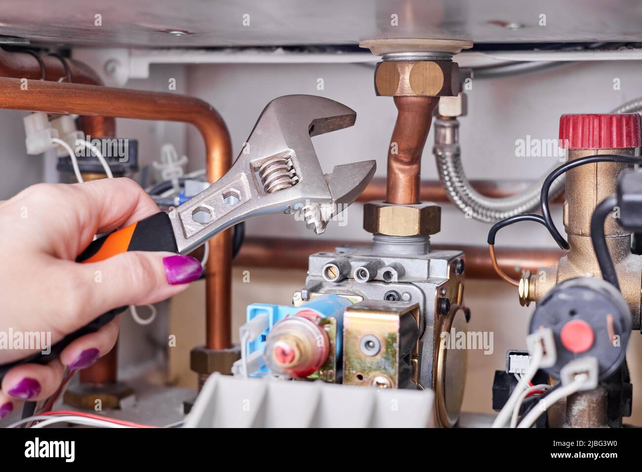 La fille va réparer la chaudière à gaz à l'aide d'une clé réglable Photo  Stock - Alamy