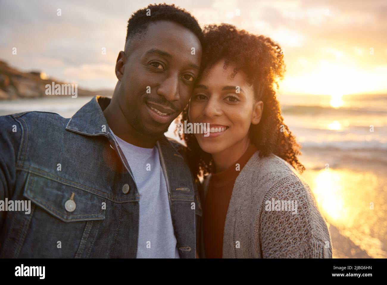 Jeune couple multiethnique aimant prenant des selfies sur une plage au coucher du soleil Banque D'Images